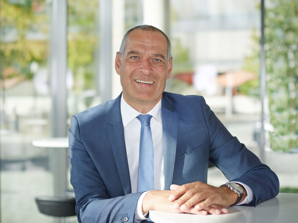 Ralf Tillmann steht an Counter und blickt in die Kamera